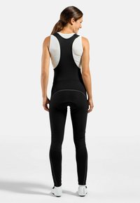 Svarte sykkelshorts med bib-design, tettsittende passform, pustende mesh-top og polstring i setet. Har flate sømmer og reflekterende detaljer.