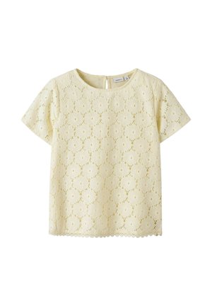 Krem bluzica s kratkimi rokavi iz čipke z rožnim vzorcem, okrogel izrez in zapenjanje na gumbe na zadnji strani, primerna za vsakodnevne ali bolj svečane priložnosti.