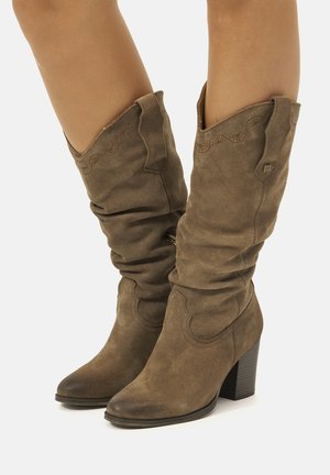 Bottines en daim marron avec un design décontracté, bout pointu et talon carré de 7,5 cm. Coutures décoratives le long du bord supérieur.