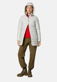 Giacca imbottita grigio chiaro con cappuccio, cerniera frontale e piccoli dettagli arancioni, indossata sopra un maglione rosso a maglia e pantaloni verde oliva.