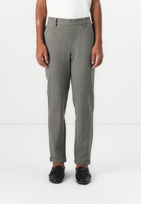 Šedé kalhoty se střihovým vzorem houndstooth, zúžené nohavice, poutka na pásek a ohrnuté manžety, spárované s černými botami.