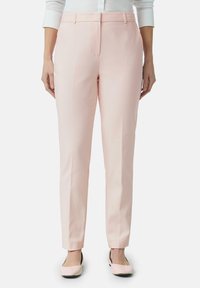 Pantaloni su misura in morbido tessuto rosa. Presentano un frontale piatto, tasche laterali e gambe affusolate che terminano alla caviglia, abbinati a ballerine coordinate.