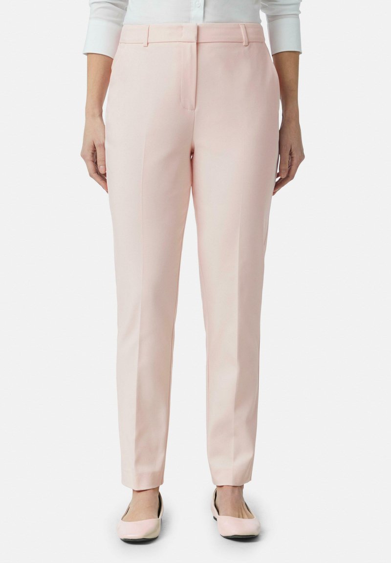 Pantaloni su misura in morbido tessuto rosa. Presentano un frontale piatto, tasche laterali e gambe affusolate che terminano alla caviglia, abbinati a ballerine coordinate.