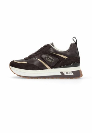Donkerbruine en beige lage sneaker met witte zool, suède en leren panelen, merklogo aan de zijkant en trekbandje aan de hiel.