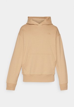 Beige hooded sweatshirt made of soft fabric, featuring a front pocket and ribbed cuffs, with a small logo on the left chest area.