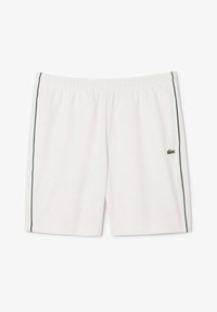 Shorts de sport blancs avec une ceinture élastique, présentant des bandes latérales vertes et un petit logo sur le côté gauche. Tissu lisse et léger.