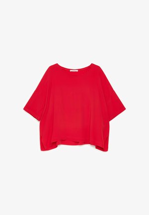 Blouse rouge à manches courtes, coupe ample, col rond et fentes latérales à l'ourlet.