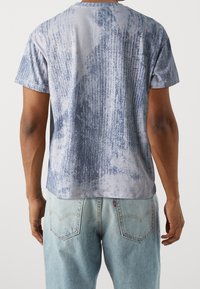 Modré a šedé tričko s vzorem vyrobené z měkké tkaniny, s kulatým výstřihem a krátkými rukávy, s volným střihem a texturovaným designem.