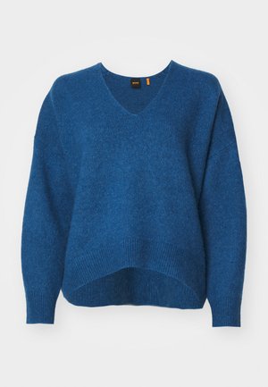 Sinine kudum, millel on V-kaelus, ülekaaluline lõige, langenud õlad ja soonikserv. Pehme tekstuur ja veidi lahti silhouette.