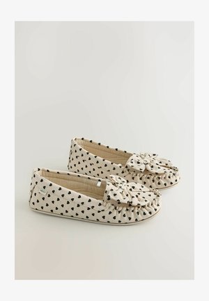 Beige fabric slippers with black heart pattern, bow accent on the front, soft texture, rounded shape, and gathered stitching detail.