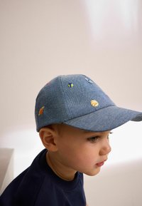 Denimkeps med en böjd skärm, dekorerad med färgglada broderade planeter. Har en klassisk sexpaneldesign och texturerad tyg.