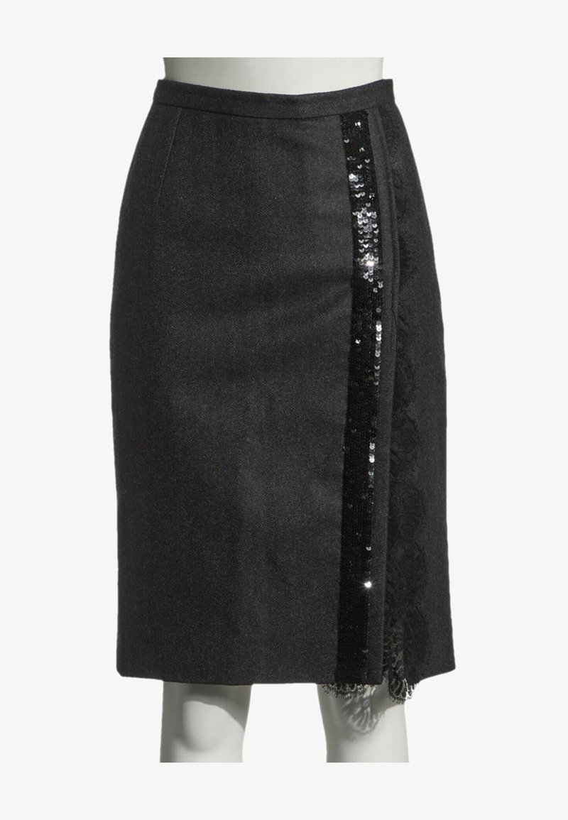 Jupe noire longueur genou avec une bande verticale de sequins noirs et des détails en dentelle sur le côté droit.