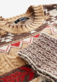 Pull en tricot avec col rond, teintes chaudes de marron et de crème, motifs texturés, designs géométriques avec des accents rouges et une finition douce.