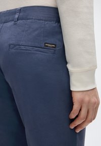 Παντελόνι ναυτικού μπλε με λεία υφή, που διαθέτει πίσω τσέπη με ραφές και μαύρη ετικέτα με την επιγραφή "SCOTCH & SODA".