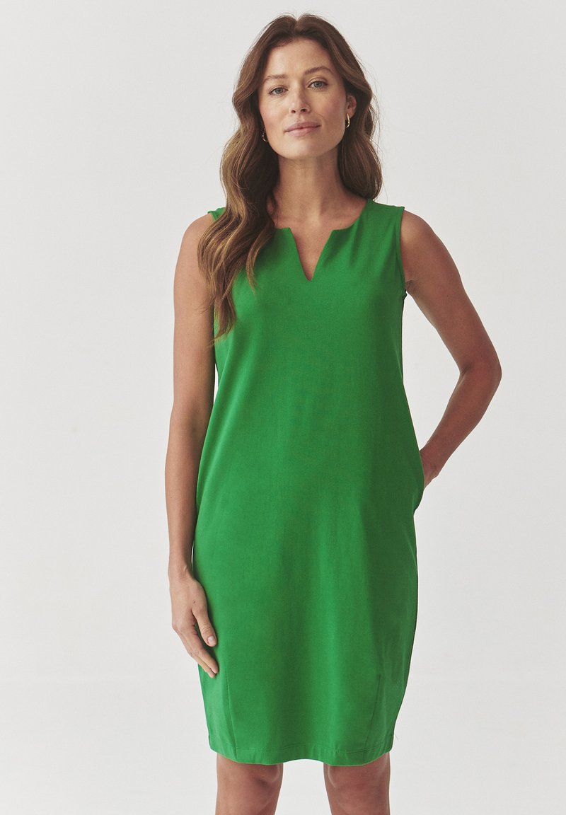 Green sleeveless dress with a v-neckline, straight silhouette, smooth texture, and side pockets, featuring clean lines and a solid color.