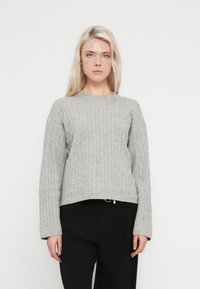 Világosszürke, kötött pulóver kerek nyakkivágással, hosszú ujjal és enyhén rövidített szegéllyel. Puha tapintású, bordás díszítéssel.