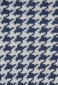 Stickad tyg med ett houndstooth-mönster i mörkblått och grädde, med en texturerad yta och en konsekvent upprepning av designen.