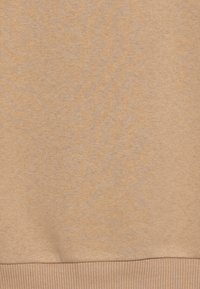 Béžová bavlněná mikina s hladkou texturou, s žebrovaným lemem na spodní straně a jemnou variací odstínů.