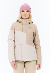 Beige wasserdichte Jacke mit einem Farbblockdesign; verfügt über eine Reißverschlusstasche, eine verstellbare Kapuze und elastische Bündchen. Getragen mit einer pinken Mütze.