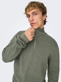 Pull gris-vert à fermeture éclair, col montant, en tissu tricoté texturé, manches longues, avec un motif côtelé subtil aux poignets.