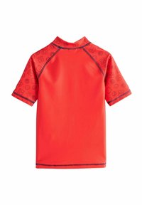 Rash guard rosso a maniche corte con una texture liscia, caratterizzato da un design a motivo con vari icone lungo le maniche e il colletto.