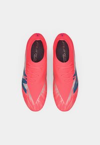 Pari kenkä punainen urheilujalkine sinisin ja hopeisin yksityiskohdin, nähtynä ylhäältä valkoisella taustalla.