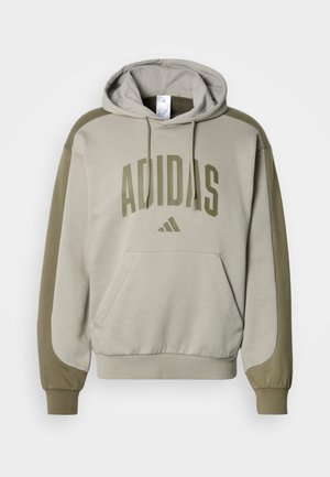 Sudadera con capucha confeccionada en tela suave, con cuerpo beige y mangas verde oliva, gran logo "ADIDAS" y bolsillo frontal tipo canguro.