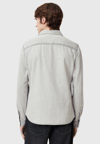 Helle graue Jeanshemd mit langen Ärmeln, einem klassischen Kragen und geknöpften Manschetten. Verfügt über eine subtile Textur und einen abgerundeten Saum.