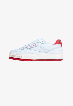 Baskets basses blanches Reebok avec semelle rouge, languette de talon rouge et logo Reebok sur le côté et le talon, présentées en profil latéral sur fond blanc.