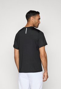 Čierne športové tričko s krátkymi rukávmi, so vstupom na chrbte a plochými švami pre pohodlie. Vyrobené z ľahkého, priedušného materiálu.