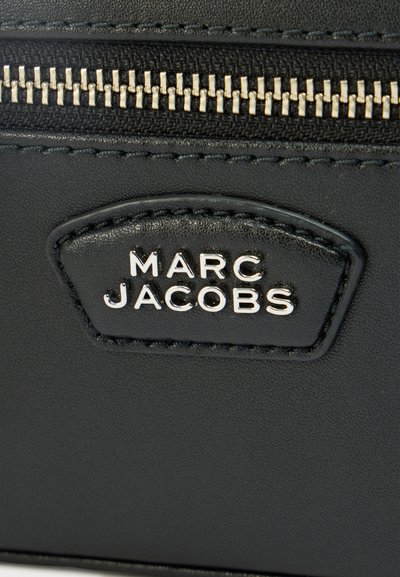 Μαύρο δερμάτινο πορτοφόλι με ασημί φερμουάρ, ανάγλυφο λογότυπο και λεπτομερή ραφή. Λείο υλικό με στιβαρό σχήμα.