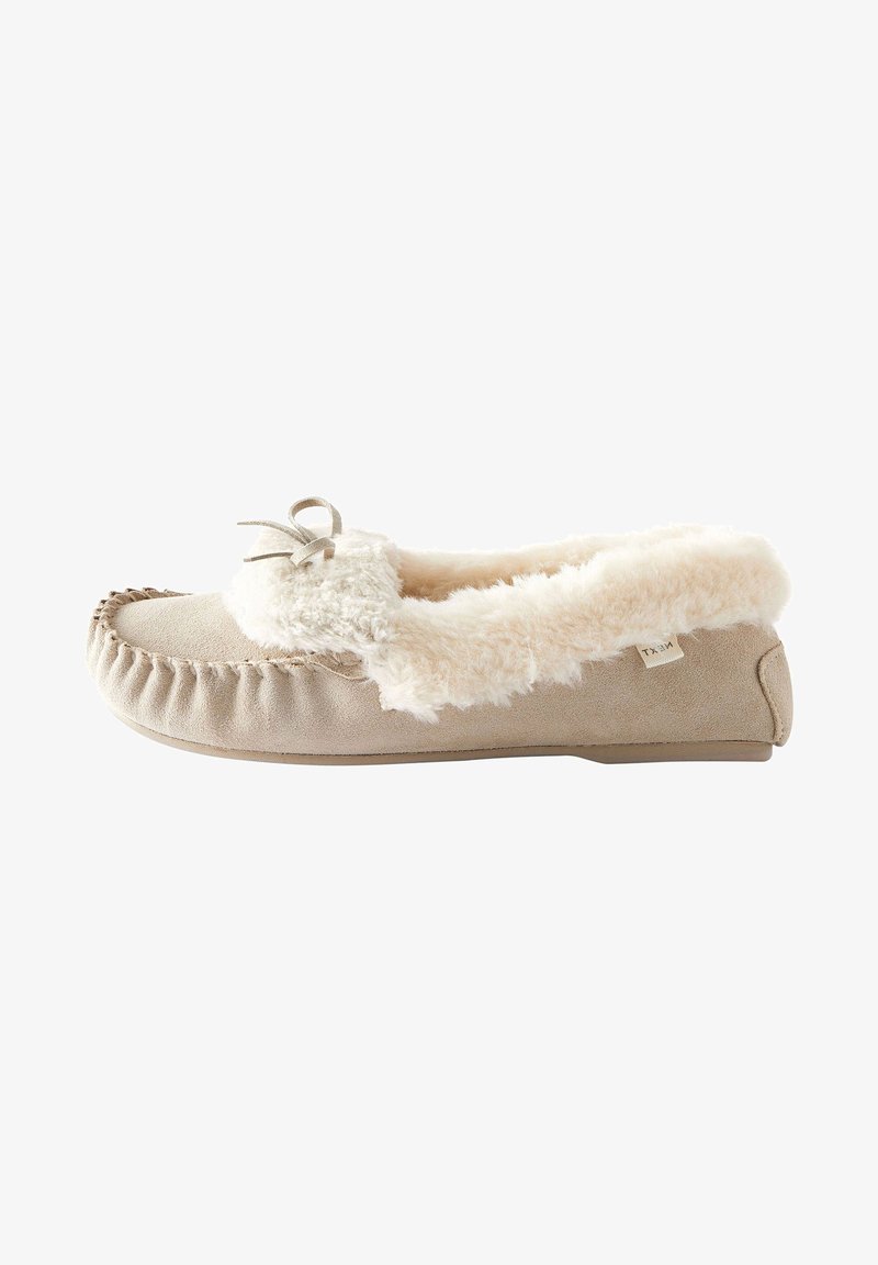 Beige suede slipper with white faux fur lining, a rounded toe, decorative bow, and stitched detailing along the edges. Flat sole.