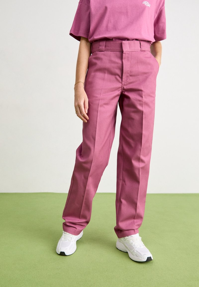 Roze op maat gemaakte broek van gladde stof, met een hoge taille, rechte pijpen en zijzakken, gecombineerd met witte sneakers.