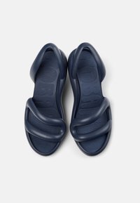 Navy blue sandals with a flexible, wavy strap design, textured footbed, and a rounded shape. Made from durable rubber material.