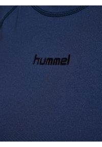 Close-up of navy blue fabric with black embossed "hummel" logo centered on the chest area of a garment.