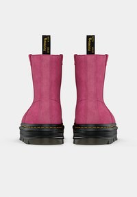 Pink suede ankle boots with a black thick sole, featuring yellow stitching and pull tabs on the back for easy wear.