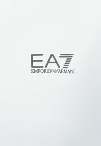 Fehér háttér fekete logóval, amelyen az "EA7" és az "EMPORIO ARMANI" különböző betűtípusokban szerepel, minimalista és modern dizájnt bemutatva.