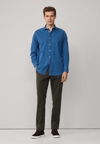 Blauwe denim button-up shirt met lange mouwen, gecombineerd met olijfgroene broek en donkere sneakers. Eenvoudig ontwerp, standaard pasvorm.
