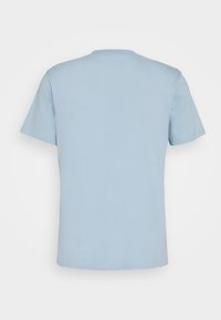 Camiseta de cuello redondo de manga corta en color azul claro, vista desde atrás, sobre un fondo blanco.