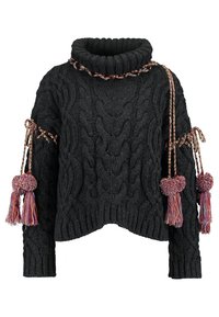 Maglione nero a maglia cable con colletto alto, caratterizzato da dettagli intrecciati e due pompon colorati sulle maniche. Design cropped.
