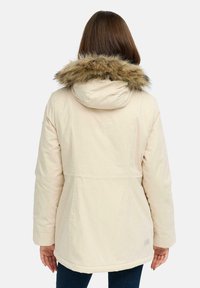Veste d'hiver beige avec capuche, dotée d'une fourrure sur le col, manches longues et coupe droite. Texture lisse, peu de détails à l'arrière.