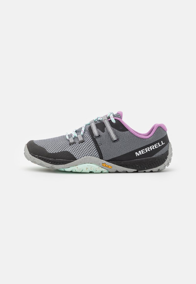 Zapatilla deportiva gris y negra con parte superior de malla, acentos morados, suela de goma y cordones reflectantes. Presenta la marca Vibram en la suela.