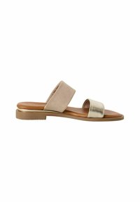 Sandal s otvorenom prstima od suede i metalika; ima dvije trake - jedna bež, jedna zlatna - na ravnoj smeđoj potplati. Glatka tekstura, minimalna oprema.