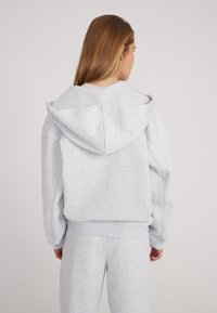 Grijze sweatshirt met een capuchon en zijzakken, met ribgebreide manchetten en onderrand. Ontworpen voor een relaxte pasvorm van zacht, textuurachtig stof.
