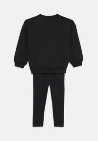 Sweatshirt negru din bumbac, cu mâneci lungi, guler rotund și manșete cu nervuri, purtat cu leggings negri elastici asortați. Design simplu, fără modele.