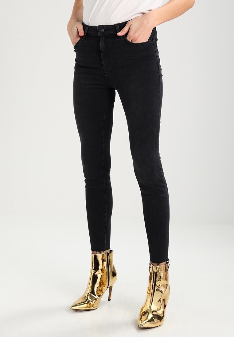 Černé skinny džíny s vysokým pasem vyrobené z denimu, s knoflíkovým zapínáním a předními kapsami, spárované s metalickými zlatými kotníkovými botami.