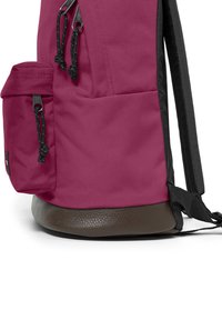 Batoh v tmavě růžové látce s černými akcenty, obsahující jednu boční kapsu a texturované hnědé dno. Obsahuje nastavitelné popruhy.