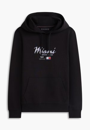 Fekete kapucnis pulóver első zsebbel, "Miami 2026 május 1-3" felirattal, Cadillac logóval és Tommy Hilfiger zászlóemblémával a mellrészen.