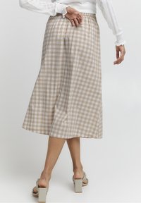 Beige ruudullinen midi-hame, jossa on pleatattu muotoilu ja joustava vyötärö, valmistettu kevyestä kankaasta. Hame ulottuu nilkkojen ylle ja sillä on virtaava siluetti.