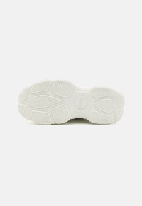 White sneaker sole with textured rubber for grip, featuring a patterned tread with varying grooves and a circular logo at the center.
